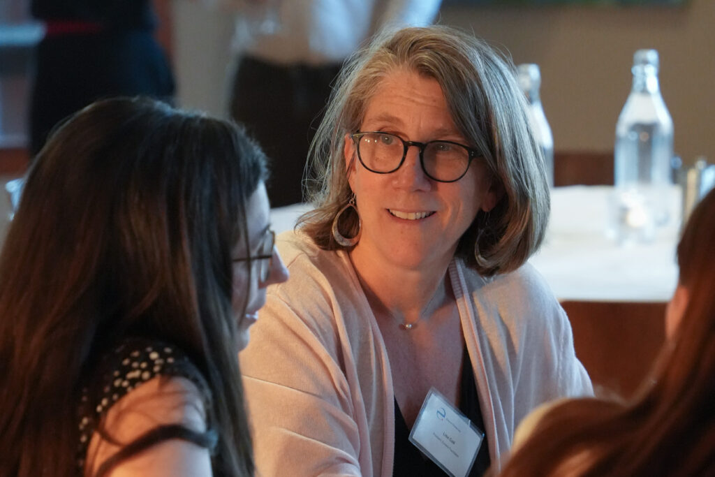 Lisa Coll, president of Eurasia Foundation, sits at a table and looks at a YPN fellow with whom she is having a discussion. 